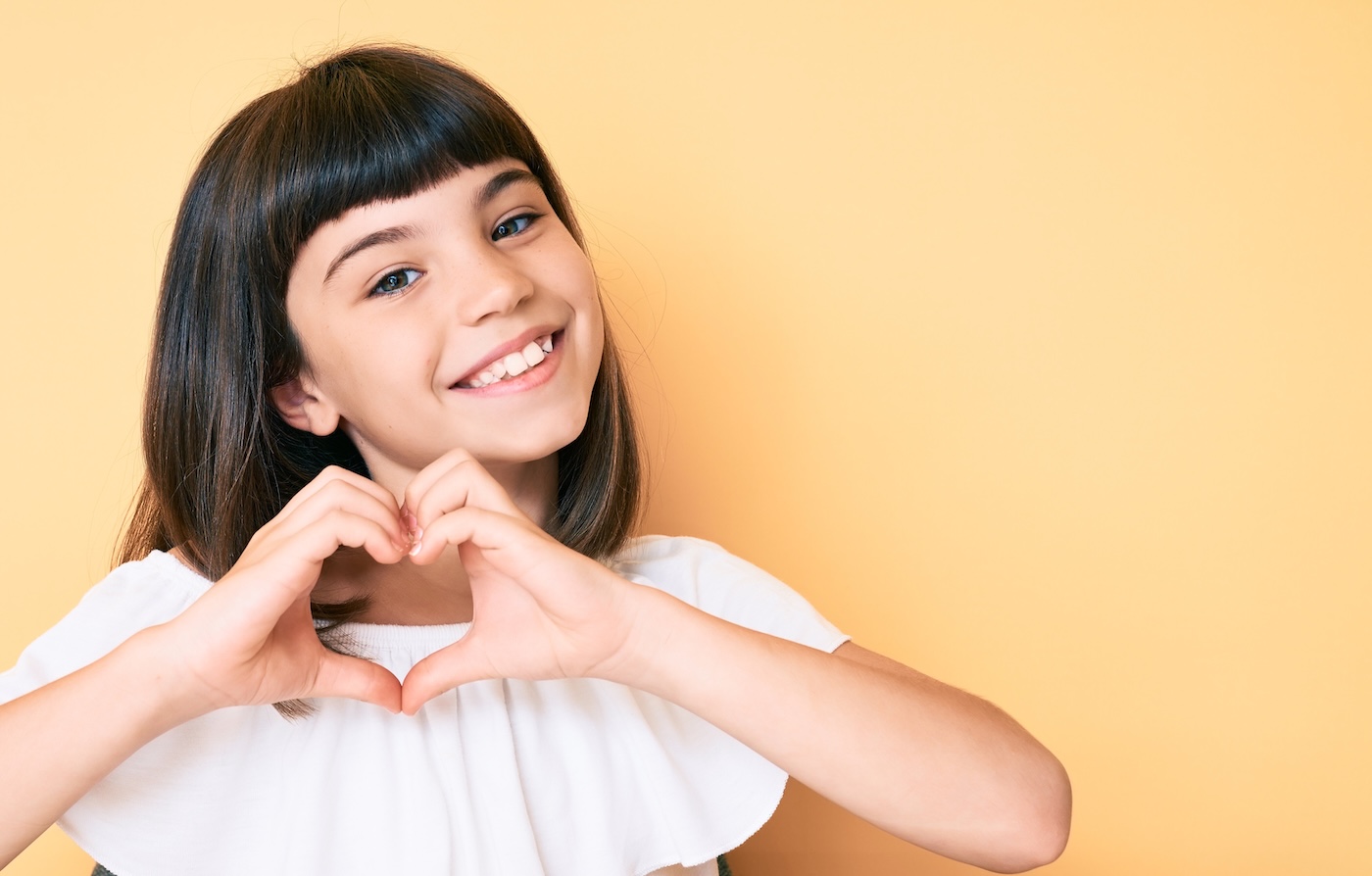 Young patient smiling and making a heart shape with her hands