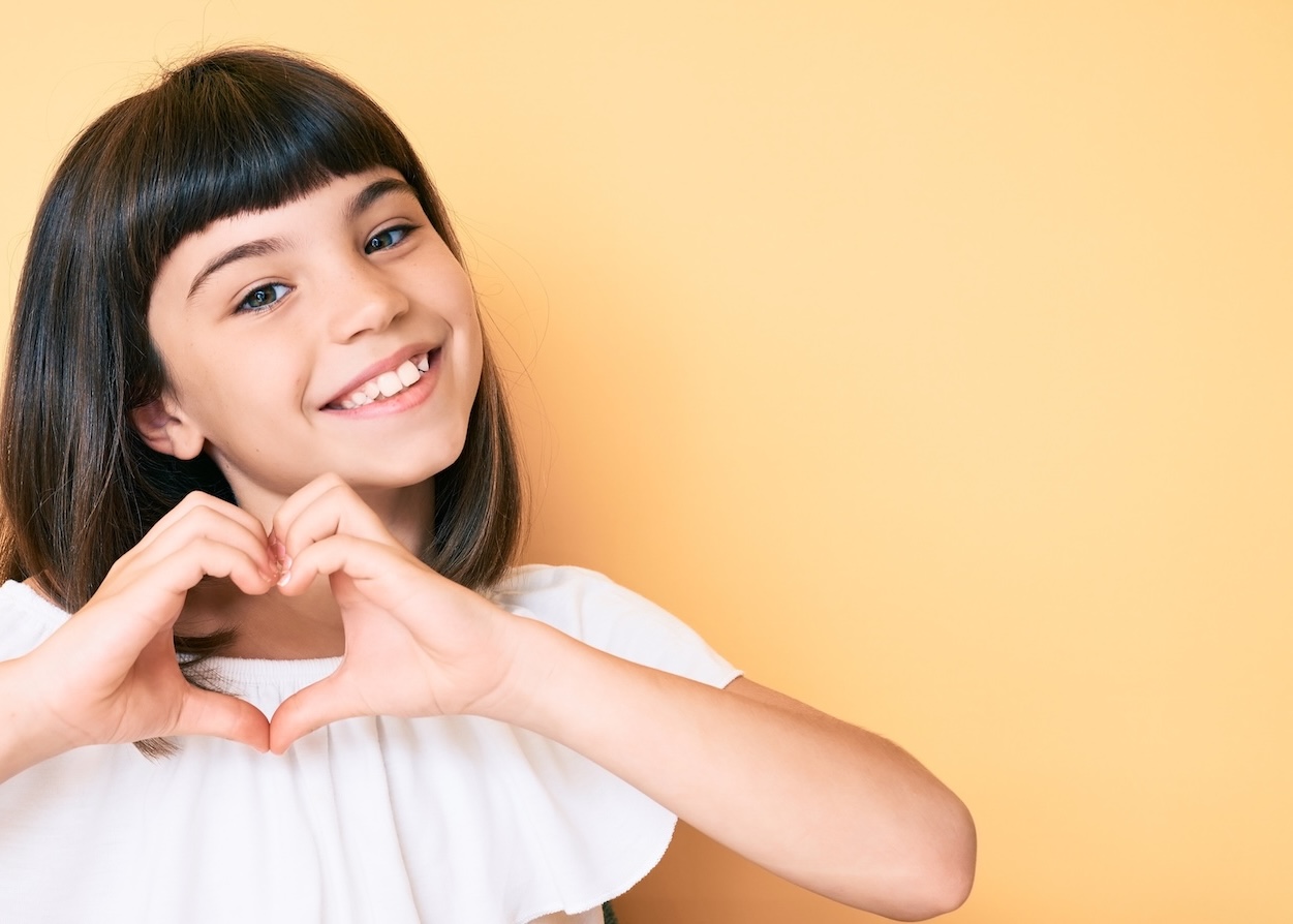 Young patient smiling and making a heart shape with her hands