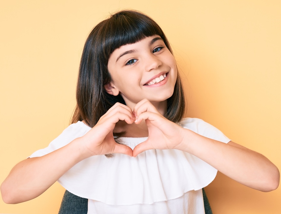 Young patient smiling and making a heart shape with her hands