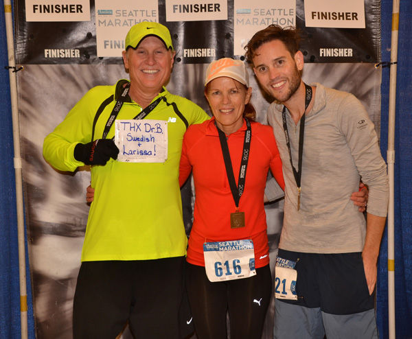 Phil, heart surgery patient, holding "Thank You" sign after running race. 