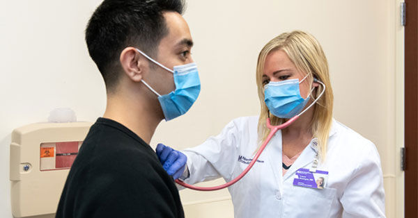 Nurse with Stethoscope on Patient Heart During Pandemic